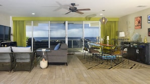 Un salon avec un canapé, des fauteuils, un téléviseur et un balcon offrant une vue agréable.