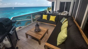 Un balcon avec un canapé, des chaises et un barbecue.