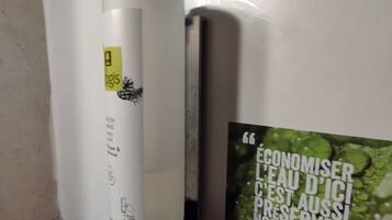 Un distributeur de gel hydroalcoolique fixé au mur, accompagné d’une affiche encourageant à économiser l’eau.