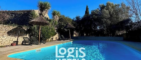 Una piscina al aire libre, sillones reclinables de piscina