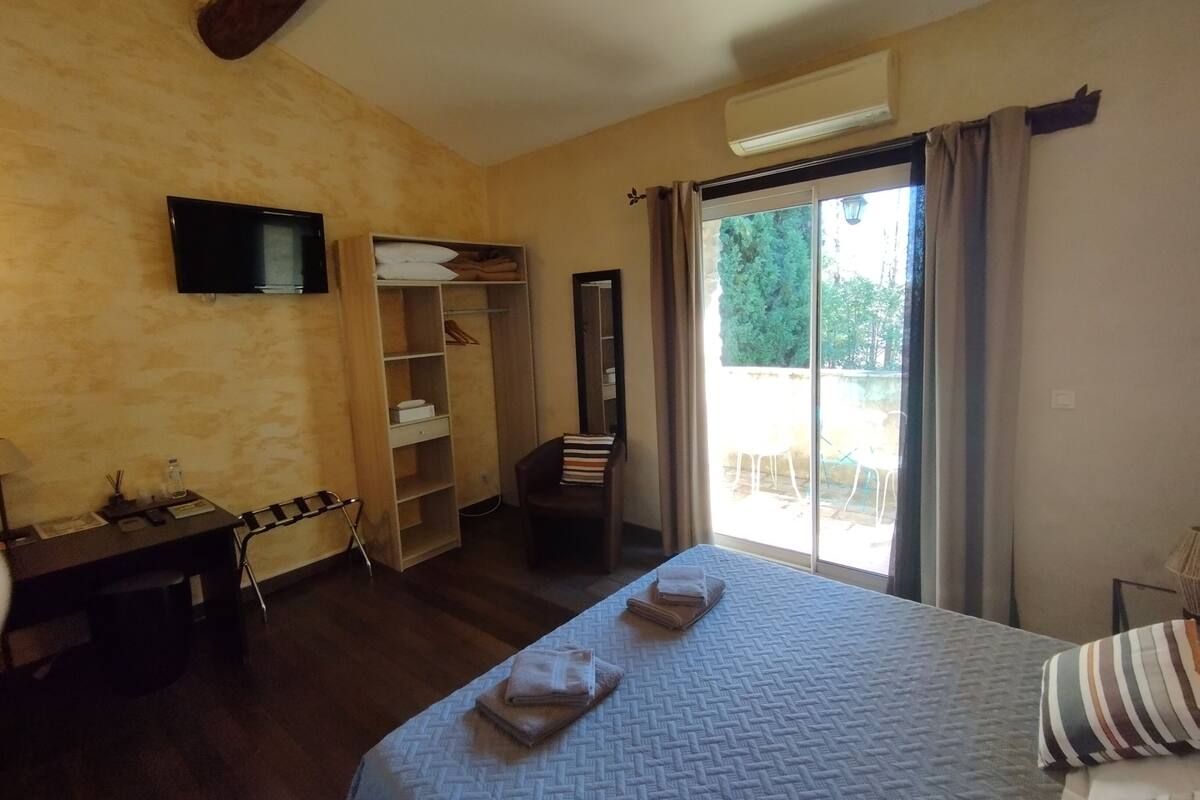 Een slaapkamer met een bed, een kledingkast, een bureau, een stoel en een televisie.