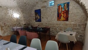Un coin repas rustique avec des murs en pierre, un plafond haut et une table mise pour le repas.
