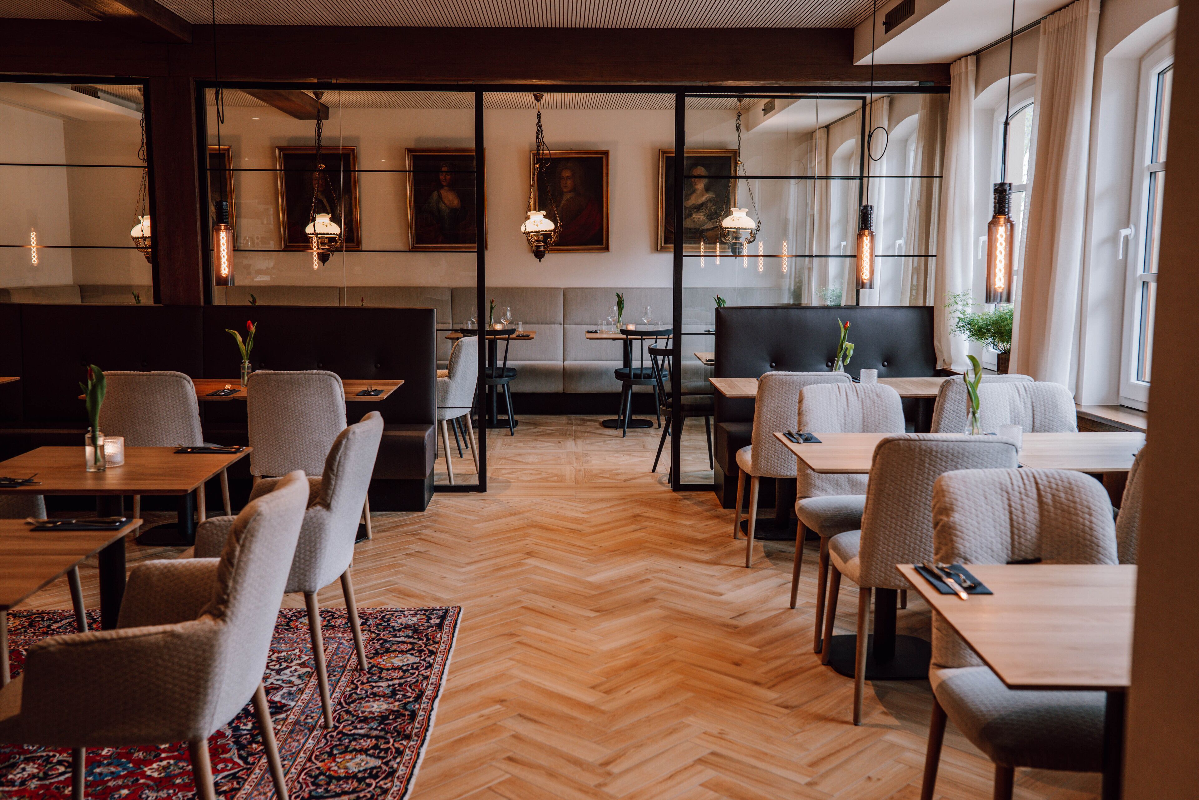 Un restaurante moderno con suelo de madera, asientos acolchados e iluminación colgante.