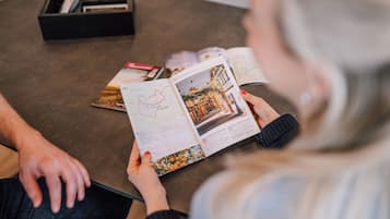 A person reading a magazine with a map and an article on a table.