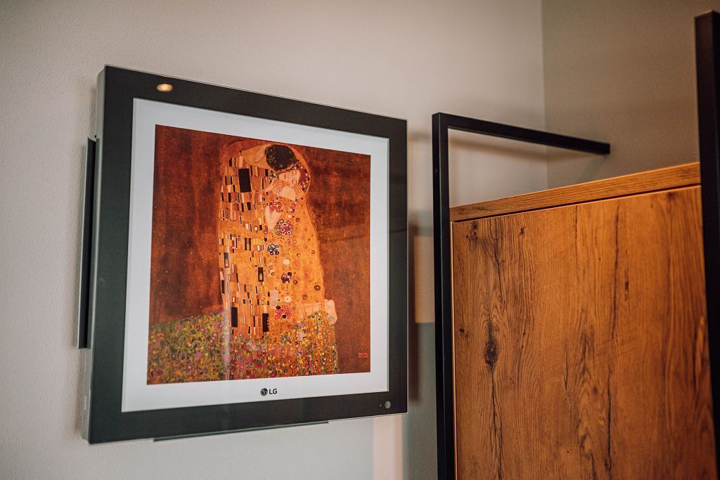 A framed artwork of a building with a unique architectural design, mounted on a wall.
