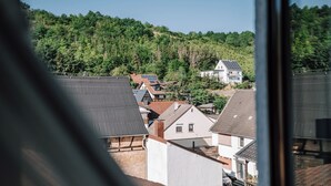 A residential area with houses, some with solar panels, and a forested hill in the background. - Schmidtburger Hof (Weiler bei Monzingen)