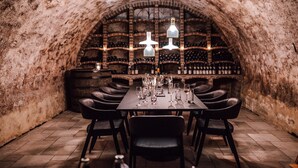 Una cantina vinicola con un lungo tavolo apparecchiato per una cena, circondata da scaffali per vini.