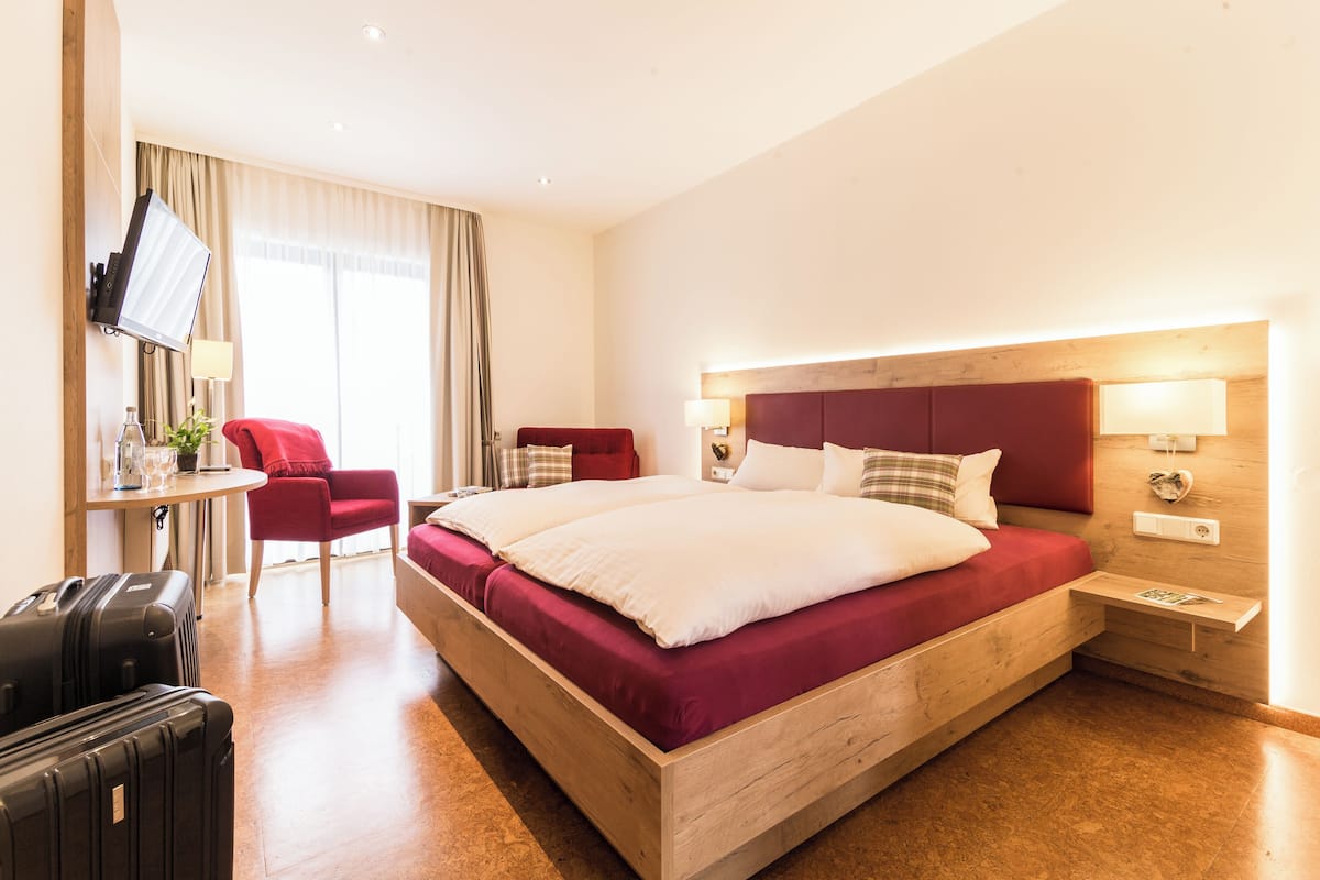 A hotel room with a wooden bed, a desk, a chair, and a TV.