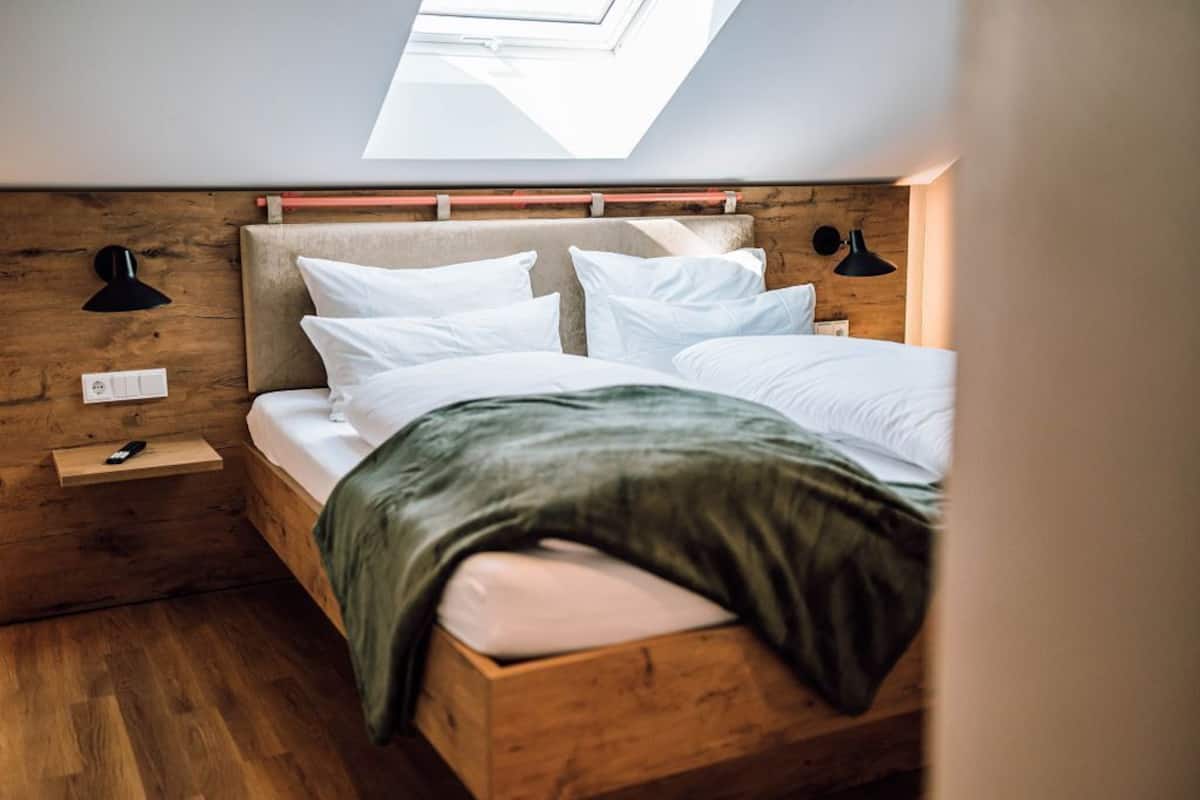 A bedroom with a skylight, wooden headboard, and bedside lamps.