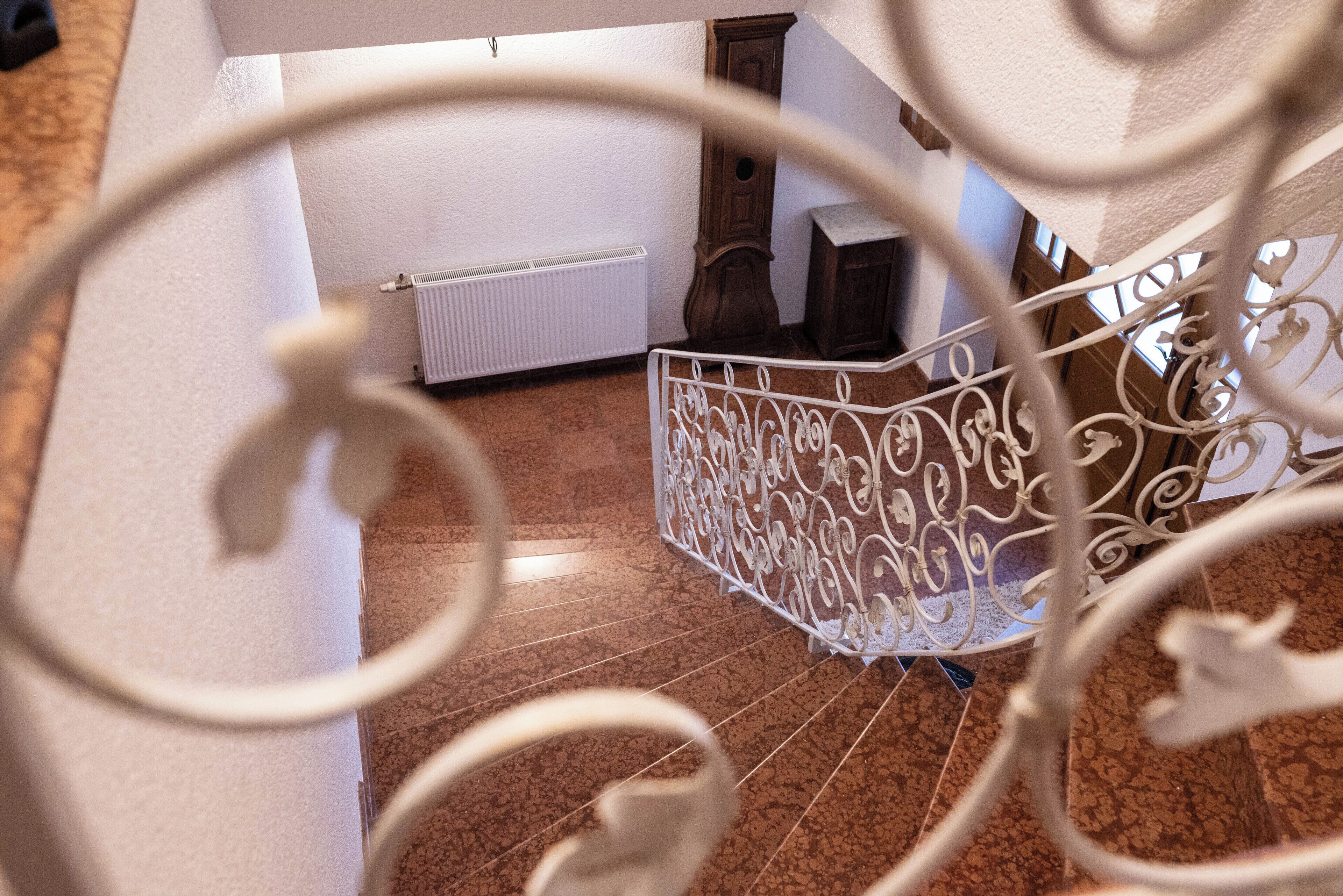 Una escalera de caracol con barandillas de metal decorativas y un radiador al fondo.