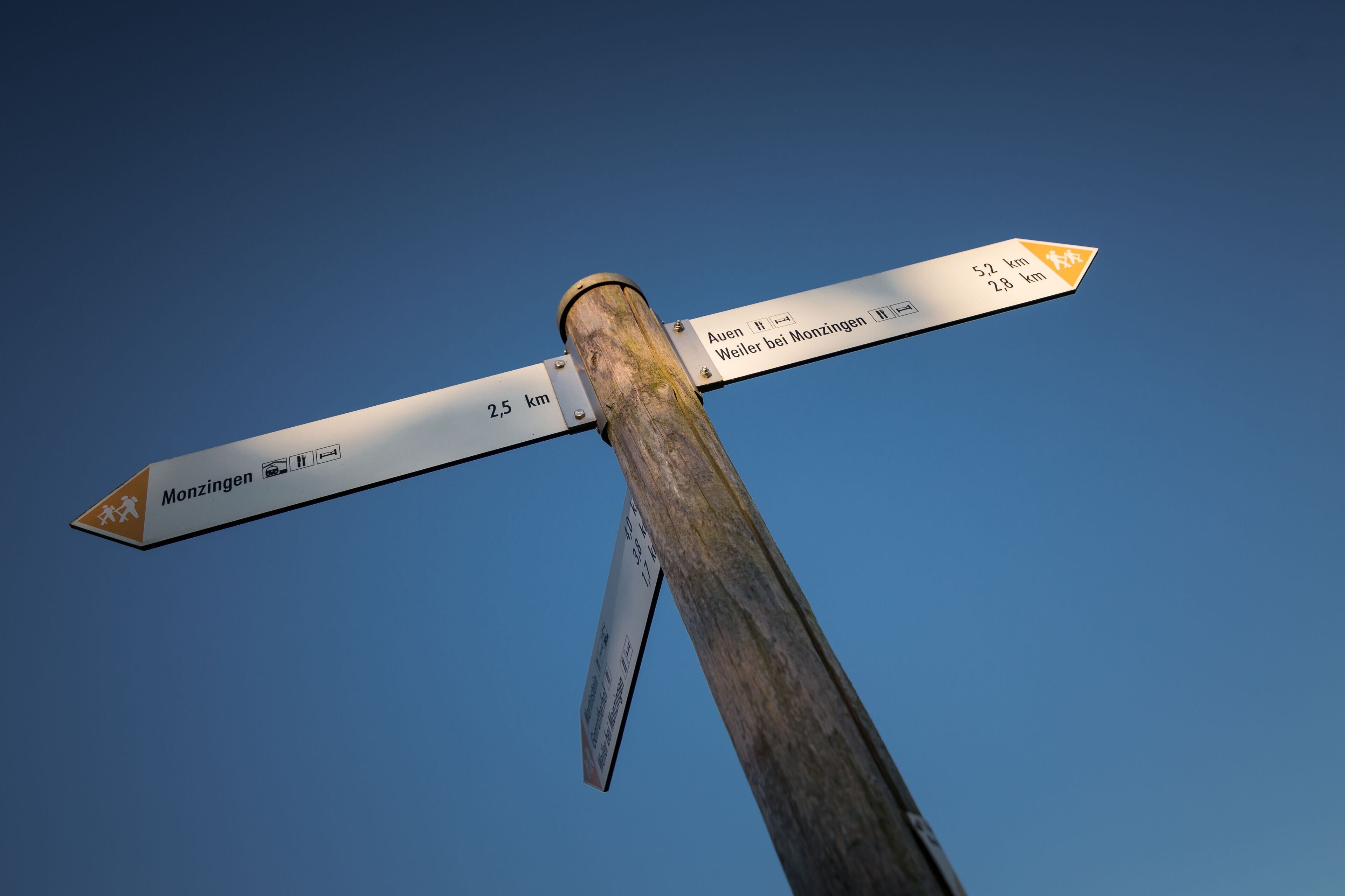 Un panneau indicateur indiquant la direction à suivre et la distance jusqu'à Monzingen et Weiler bei Monzingen.