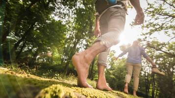 A person walking barefoot on a moss-covered rock in a forest.
