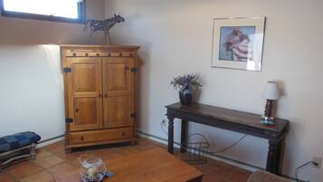 A living room with a wooden cabinet, a table with a candle, a sofa, and a framed picture on the wall.