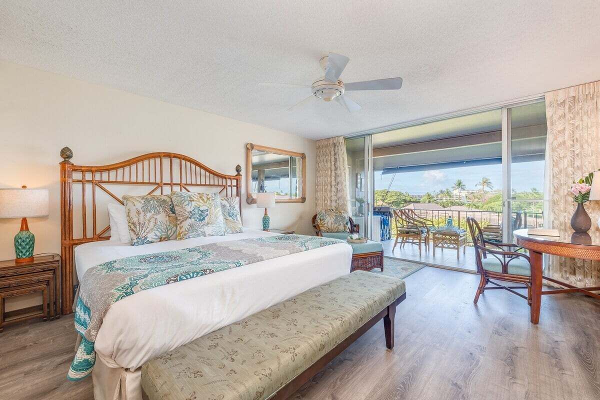 Ein geräumiges Schlafzimmer mit einem großen Bett, einem Deckenventilator, einem Balkon mit Sitzgelegenheiten und Blick ins Freie.