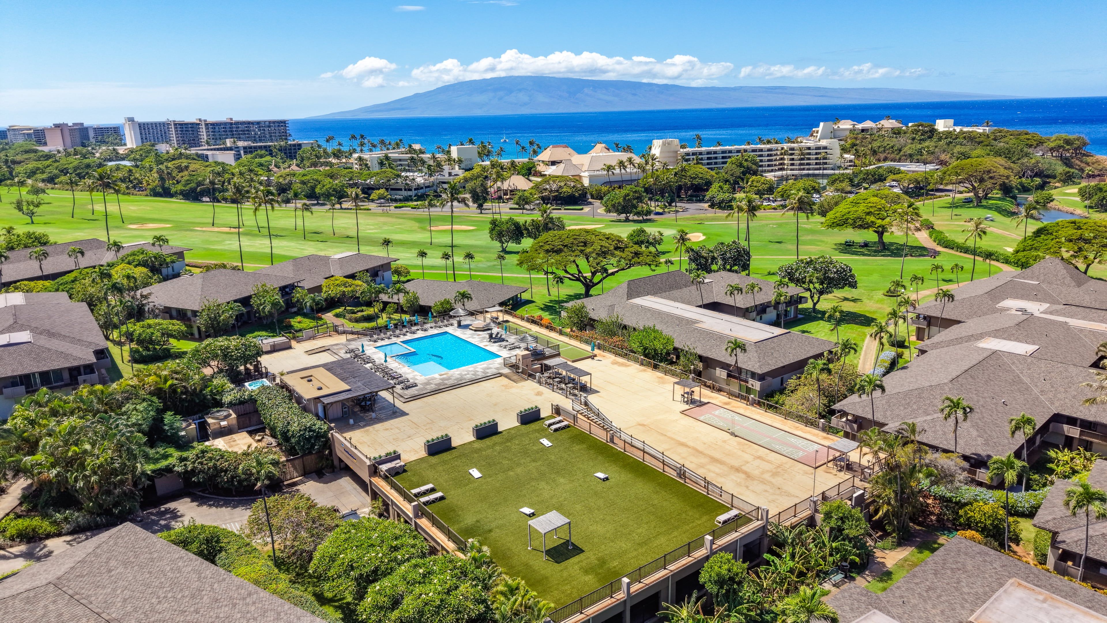 A resort with a swimming pool, multiple buildings, and a view of the ocean.