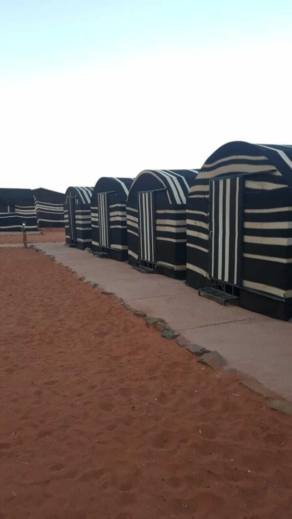 A row of striped, dome-shaped tents with a concrete pathway in between.
