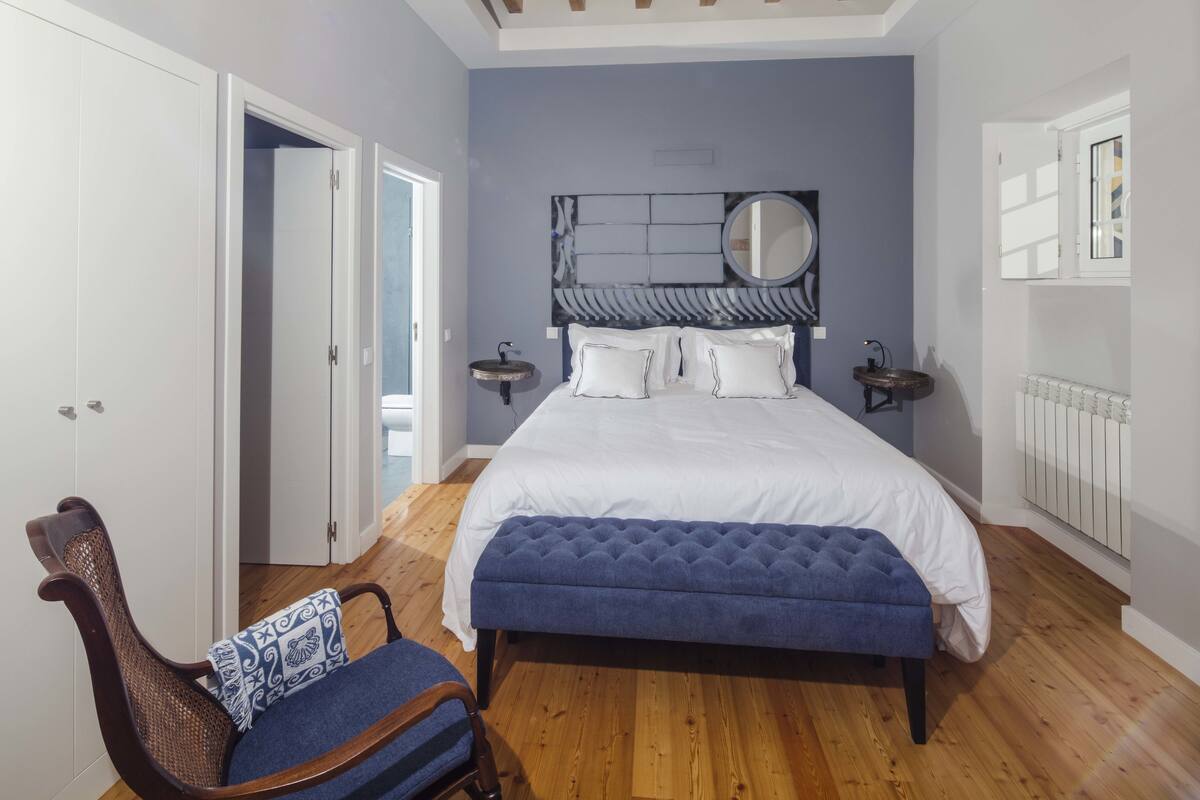 A bedroom with a bed, bedside tables, a chair, and a window.