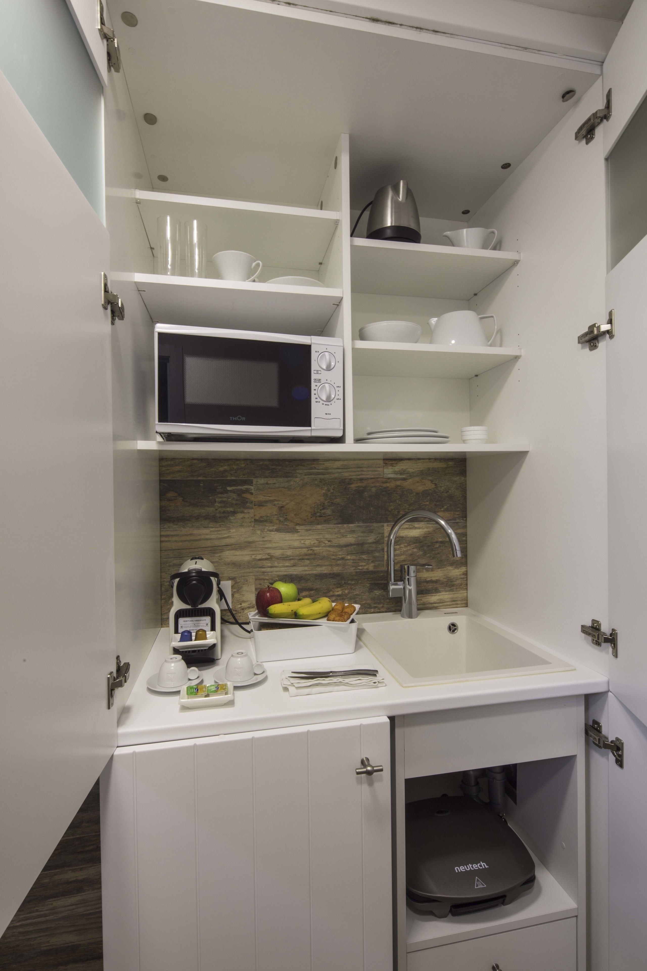 A compact kitchen with a microwave, sink, and storage cabinets.