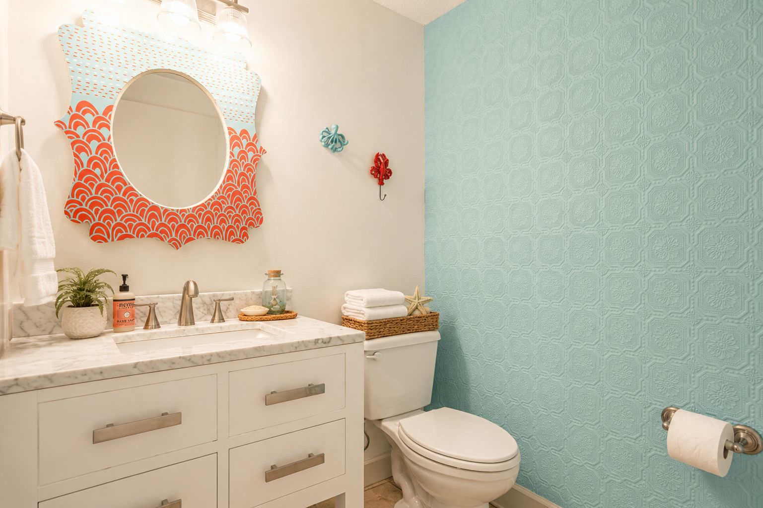 A bathroom with a white toilet, a sink with a mirror, and a patterned wall.