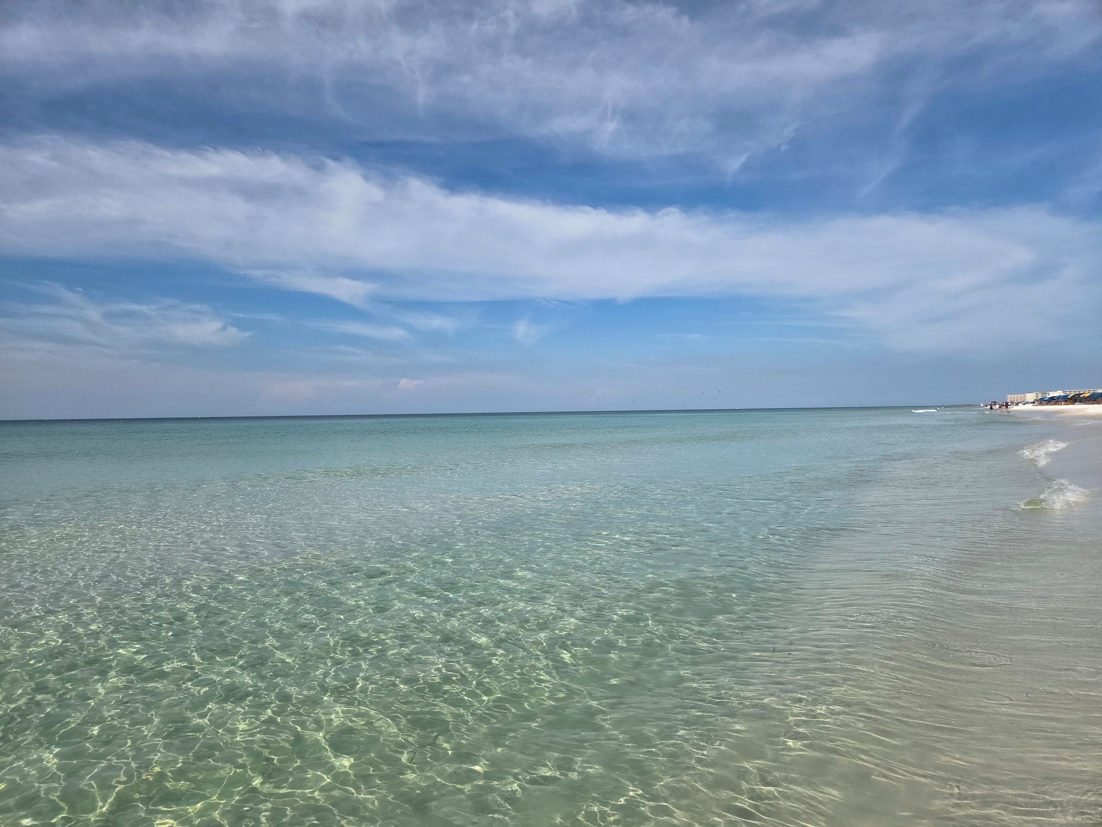 A beach with clear shallow waters and a distant shoreline.
