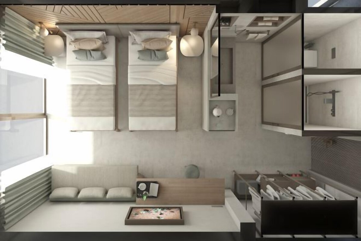 A modern, minimalist hotel room with a large bed, a seating area with a coffee table, and a kitchenette.
