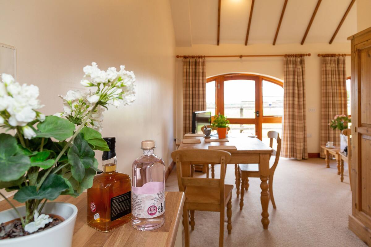 A dining area with a wooden table and chairs, a potted plant, and a bottle of water.