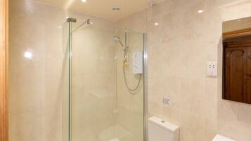 A modern bathroom with a glass-enclosed shower, a white bathtub, and a wooden cabinet.