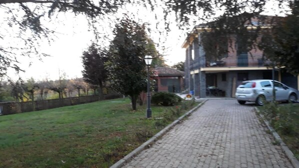 A paved pathway leading to a building with a car parked nearby. - Villa Laura (Incisa Scapaccino)