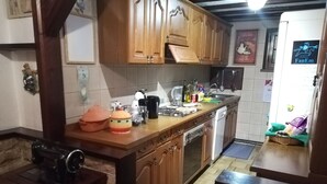 A kitchen with wooden cabinets, a stove, a sink, and various kitchen items on the counter. - Villa Laura (Incisa Scapaccino)