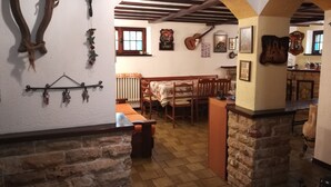 A cozy dining area with a wooden bench and table, stone walls, and a rustic kitchen in the background. - Villa Laura (Incisa Scapaccino)