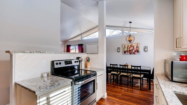 A kitchen with a built-in oven, a dining area with a table and chairs, and a view of the outdoors through a window. - ★ Easy Check-in ★ By Downtown Littleton ★ Full Kitchen ★ (Littleton)