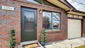 A brick house with a dark front door, a garage door, and a number '5353' on the wall. There are two small potted plants on the front steps. - ★ Easy Check-in ★ By Downtown Littleton ★ Full Kitchen ★ (Littleton)