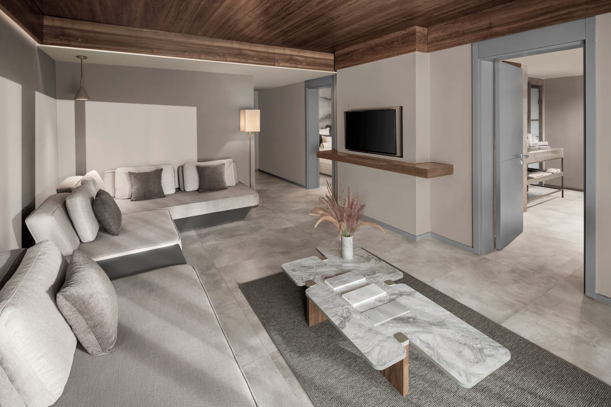 A modern living room with a sofa, a coffee table, a TV mounted on the wall, and a staircase leading to another level.