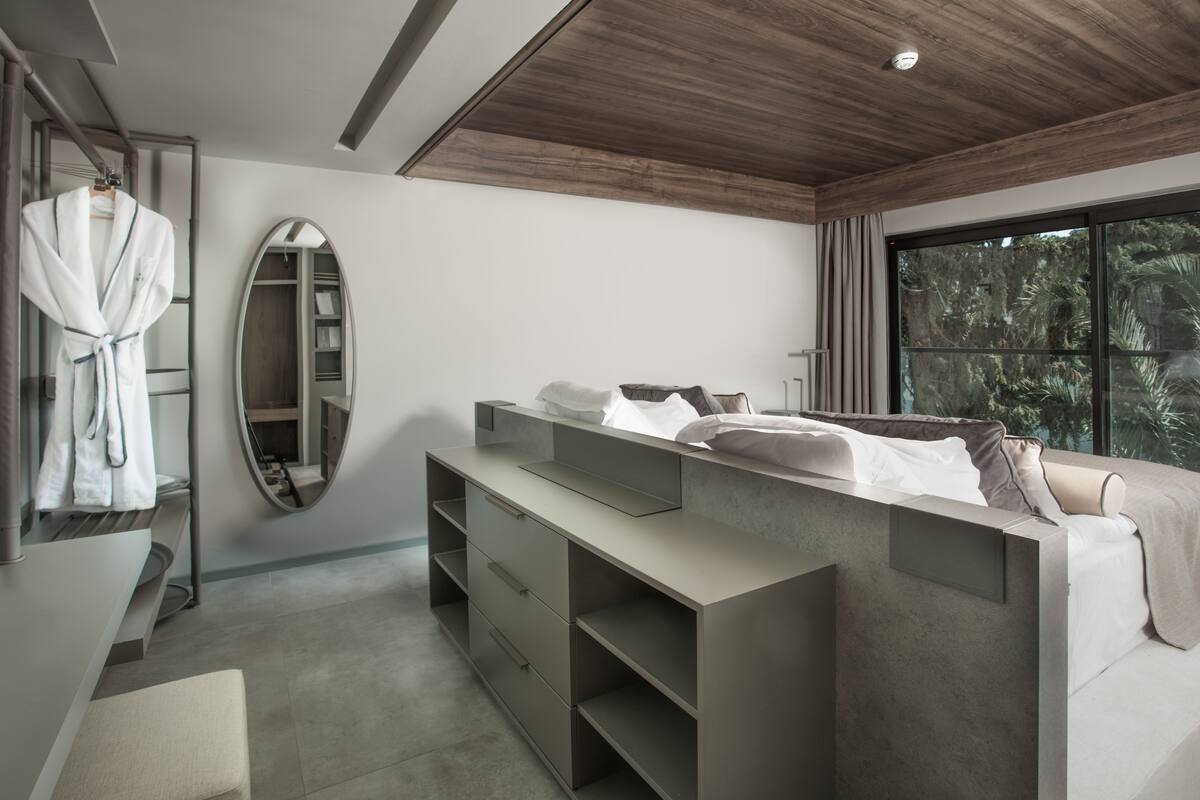 A modern bedroom with a large bed, a vanity with a mirror, and a walk-in closet.