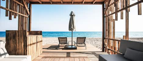 Een privéstrand, ligstoelen aan het strand, parasols, strandlakens