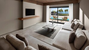A modern living room with a flat-screen TV, a wooden ceiling, a pool view, and a seating area with sofas and a coffee table. - Paloma Finesse All Inclusive (Manavgat)
