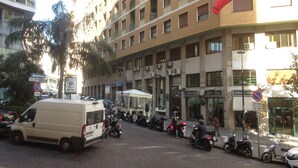 A multi-story building with a ground floor featuring shops and a parking area. - Napoli City Inn (Naples)