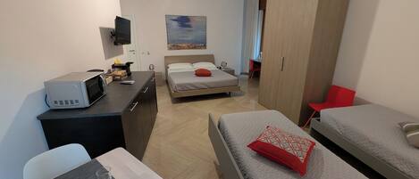 A modern hotel room with a bed, a desk, a TV, and a wardrobe.