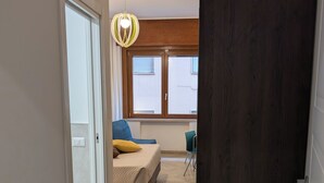 A bedroom with a bed, a chair, a window, and a door. - Napoli City Inn (Naples)
