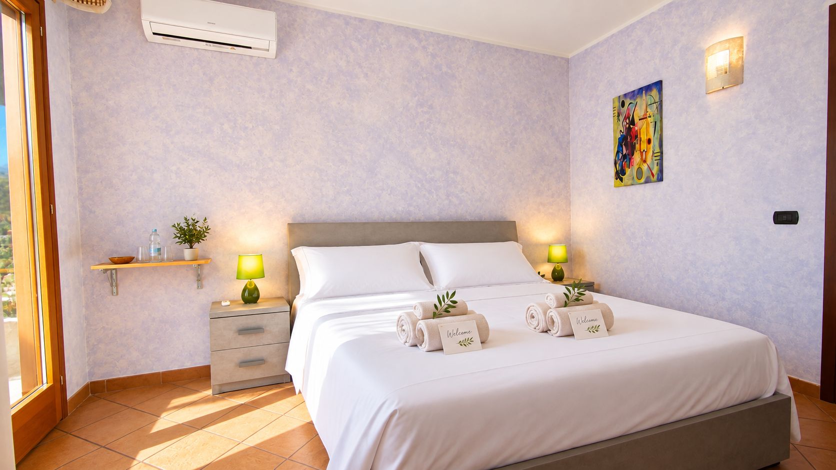 A hotel room with a bed, bedside tables, a nightstand, a wall-mounted air conditioner, a painting, and a window.