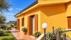 A yellow building with multiple doors, a pathway, and potted plants.