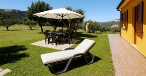 A patio with a table and chairs, a lounge chair, and a large umbrella.