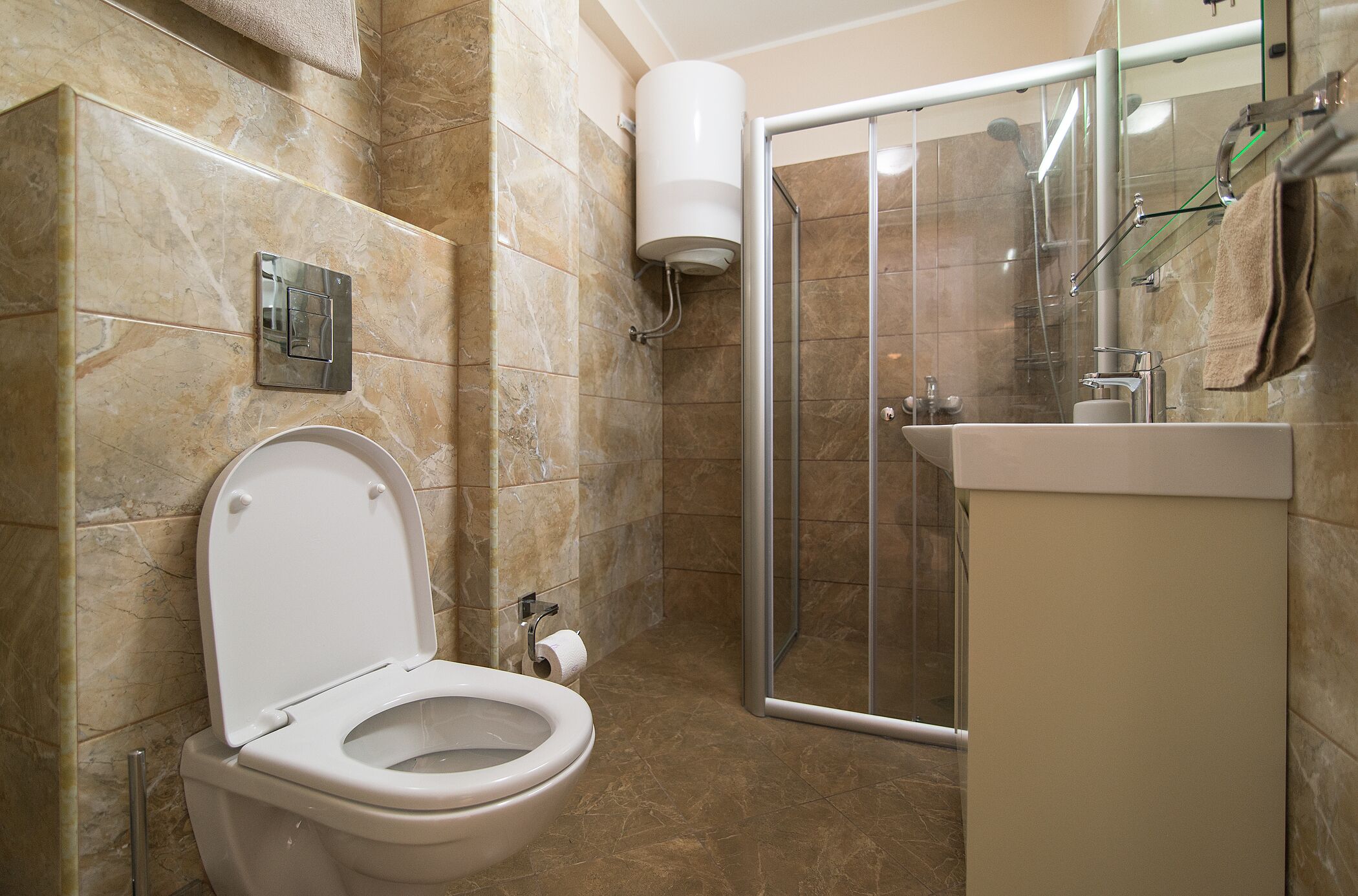 A bathroom with a toilet, a shower enclosure, and a sink.