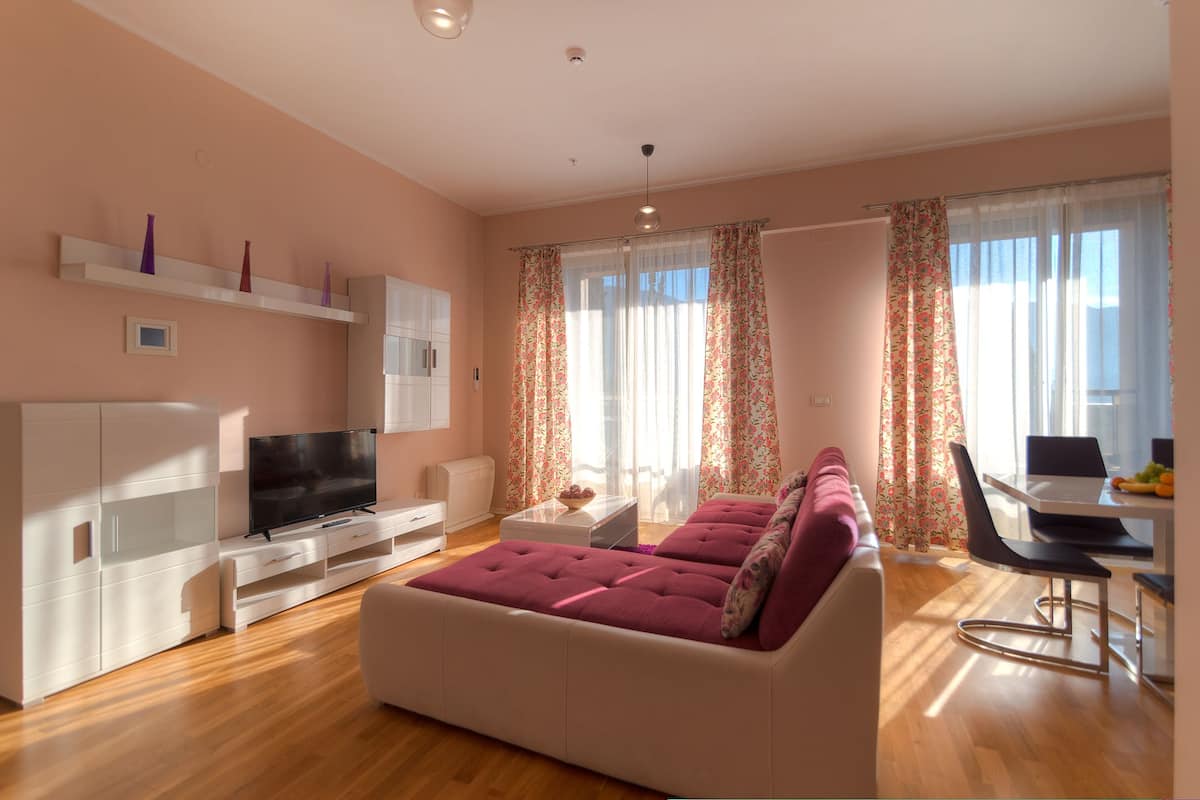 Una sala de estar moderna con un sofá, televisor y un comedor con mesa y sillas.