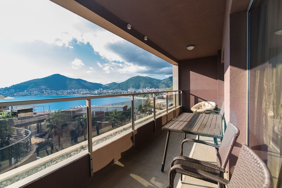 Un balcón con vistas a una ciudad, montañas y una masa de agua.
