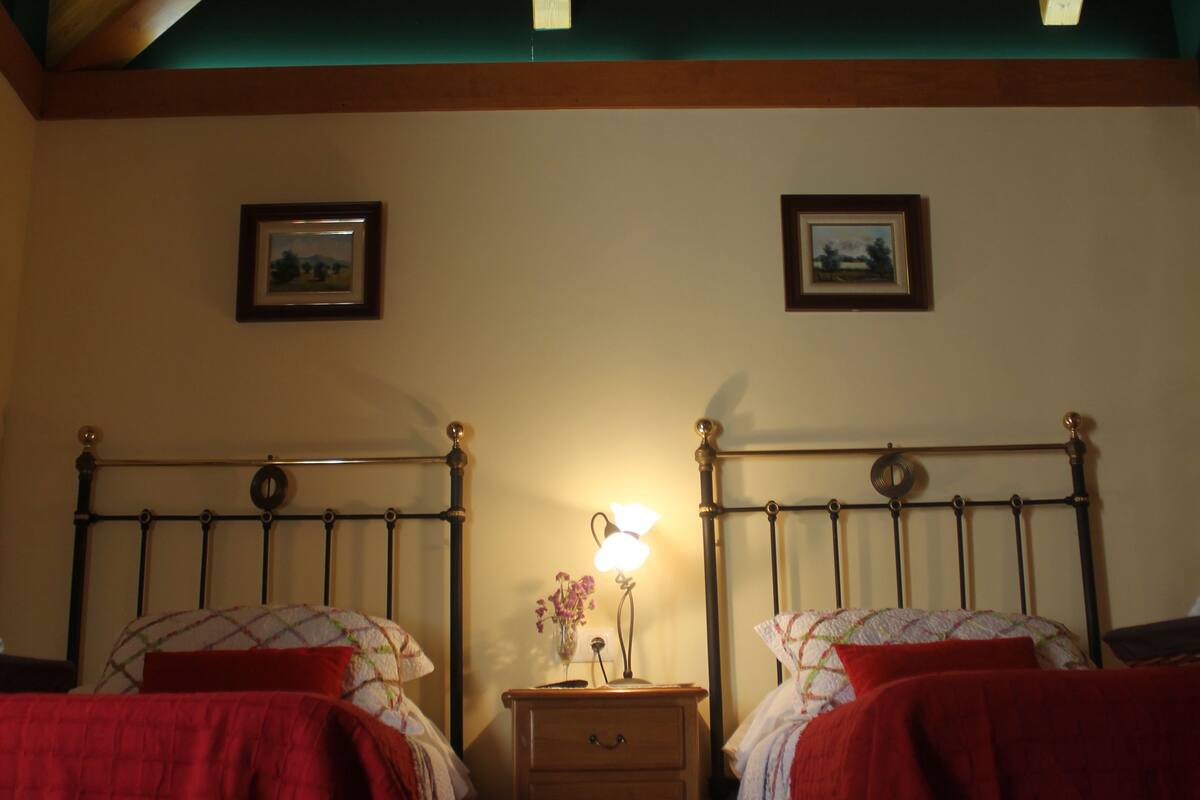 Une chambre avec deux lits, une table de chevet et une lampe.
