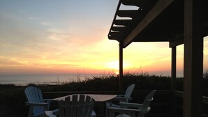 A wooden deck with Adirondack chairs facing a sunset over the ocean. - A+++ "Best Beachfront on Crescent Beach" (St. Augustine)