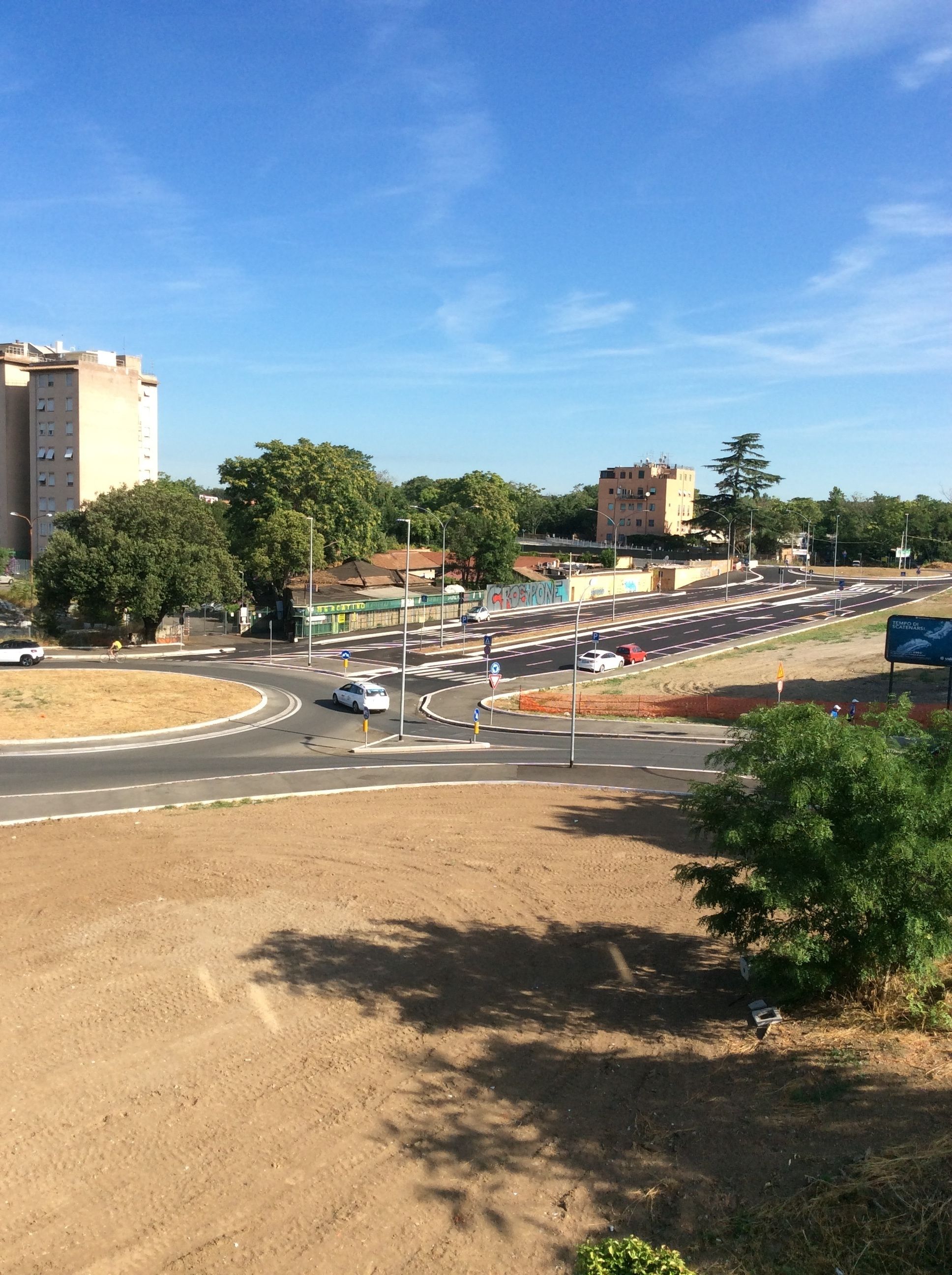 Un carrefour giratoire à plusieurs voies, entouré de bâtiments et d’arbres.
