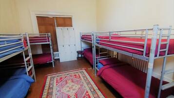 Une chambre de dortoir avec des lits superposés, un tapis à motifs et une porte avec des casiers.