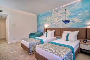 A hotel room with two beds, a large painting of a sailboat, a nightstand, and a chair.